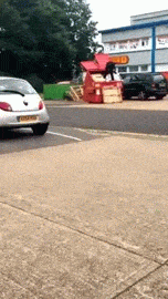 animated gif of a man standing in a skip trying to tread down a pile of cardboard